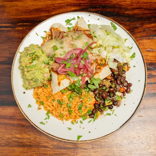 Enchiladas topped with cheese, red onions, and cilantro, served with rice, black beans, guacamole, and lettuce.